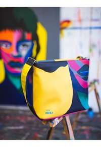 Buntes Crossbody-Bag, hergestellt aus glattem synthetischem Material. Verfügt über ein abstraktes Design mit gelben, schwarzen und mehrfarbigen Akzenten. Silberne Hardware.