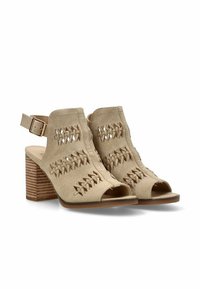 Sandalias de ante beige con punta abierta, diseño recortado y detalles trenzados. Tacón cuadrado con rayas horizontales para mayor textura. Correa de tobillo con hebilla.