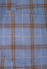 Niebieska tkanina w kratkę ma wzór siatkowy w brązowym i jasnoniebieskim kolorze, z zaokrąglonym detalem kieszeni w dolnym lewym rogu. Widoczna jest teksturowana struktura.