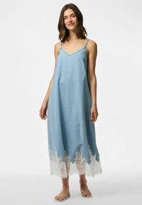 Gai zila džinsa kleita ar V veida kakla izgriezumu, regulējamiem spageti plecu siksniņām un baltu mežģīņu apdari apakšmalā. Plūstoša silueta, ceļa garuma dizains.