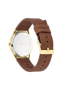 Montre à bracelet en cuir brun avec un boîtier en acier inoxydable doré, forme ronde, texture lisse et design minimaliste. Présente une boucle de marque.