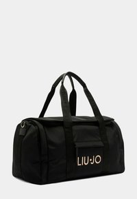 Sac de sport noir avec fermeture à glissière, fabriqué en tissu lisse. Dispose de deux poignées noires, d'un logo en doré rose et d'une poche avant.