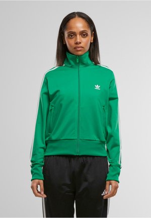 Green zip-up sports jacket with high collar, white three-striped accents on sleeves, and embroidered logo on chest. Soft, smooth fabric.