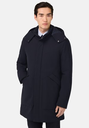 Navyblaue wasserdichte Parka mit Kapuze, ausgestattet mit einem Frontreißverschluss, Druckknöpfen und zwei seitlichen Taschen. Glatte Textur und minimalistisches Design.