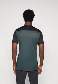 Kraťasové športové tričko s tmavozelenou sieťovinou a čiernymi akcentmi, ľahký dizajn a vetrané bočné panely pre priedušnosť.