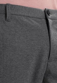 Grå byxor i texturerat tyg, med flat front, bälteshällor, knappstängning och slim fit.