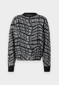 Črne dolge rokave pulover s krožnim vratom, okrašen z belim popačenim ponavljajočim se besedilom "Versace Jeans Couture" po celotni tkanini.