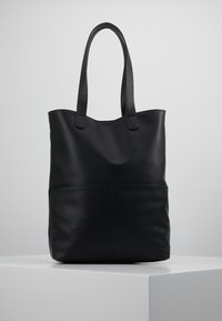 Czarna skórzana torba typu tote z dwiema mocnymi rączkami, gładką fakturą i eleganckim designem. Posiada szew wzdłuż dolnej części przodu.