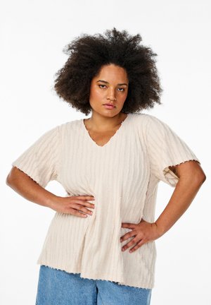 Light beige textured top with short sleeves, V-neck, and frayed hem. Features vertical ribbed pattern and relaxed fit. Paired with blue pants.