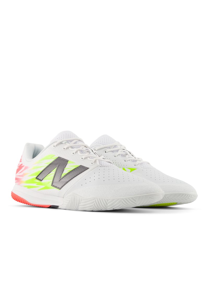 Zapatillas deportivas blancas con parte superior de malla, acentos en verde neón y rosa, suela texturizada y logotipo en el costado. Presentan cordones y perforaciones.