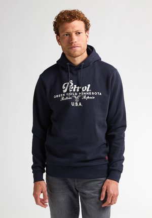 Sudadera azul marino con cordón, que presenta un gran logo impreso en blanco y texto en la parte frontal. Las mangas largas y los puños acanalados completan el diseño.