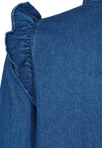 Denim odjevni predmet u tamnoplavoj boji. Ima volanasti ukras duž ramena. Izrađen je od teksturiranog denim tkanja sa suptilnim uzorkom.