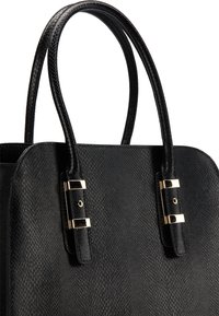 Sac à main noir avec une surface texturée, doté de poignées noires lisses et d'accents en métal doré. Détail remarquable de fermoir visible.