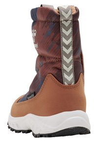 Brun och mönstrad vattentät känga med en texturerad ovandel, en kontrasterande orange nederdel och en vit sula. Reflekterande dragflik bak.