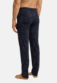 Marineblauwe pyjamabroek met een bloemenpatroon in bruintinten, gemaakt van zachte stof, met een elastische tailleband en een rechte pijpzitting.