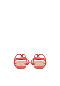 Sandales plates rouges avec plusieurs fines lanières et un petit accent doré. Texture cuir lisse et semelle plate beige. Vue arrière.