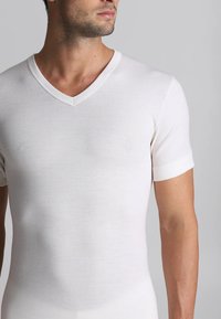 T-shirt bianco a scollo a V realizzato in morbido cotone. Caratterizzato da maniche corte con una forma aderente, una texture liscia e un design minimalista.
