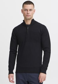 Svart zip-up genser med lange ermer, med en teksturert horisontal stripe detalj over brystet og ribbede mansjetter og kant.