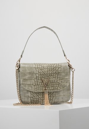 Sac à main vert clair à motif crocodile avec une bandoulière chaîne dorée, une ferronnerie en forme de V et un détail pompon. Texture lisse, forme structurée.