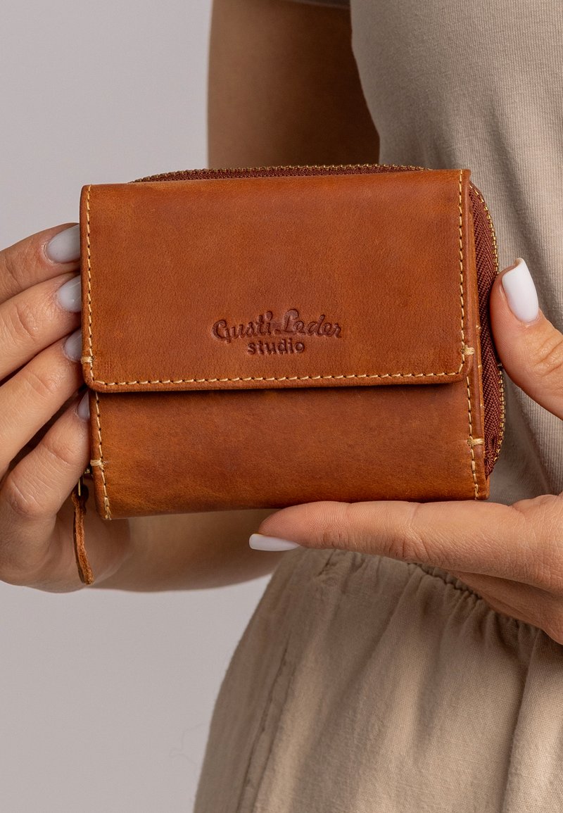 Brown leather wallet with a zip closure and embossed logo. Features stitched accents and a textured surface. Compact design for convenience.