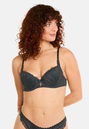 Soutien-gorge en dentelle noire avec armatures, présentant des motifs de feuilles intriqués, des bretelles réglables, des bords festonnés et un accent doré au centre.