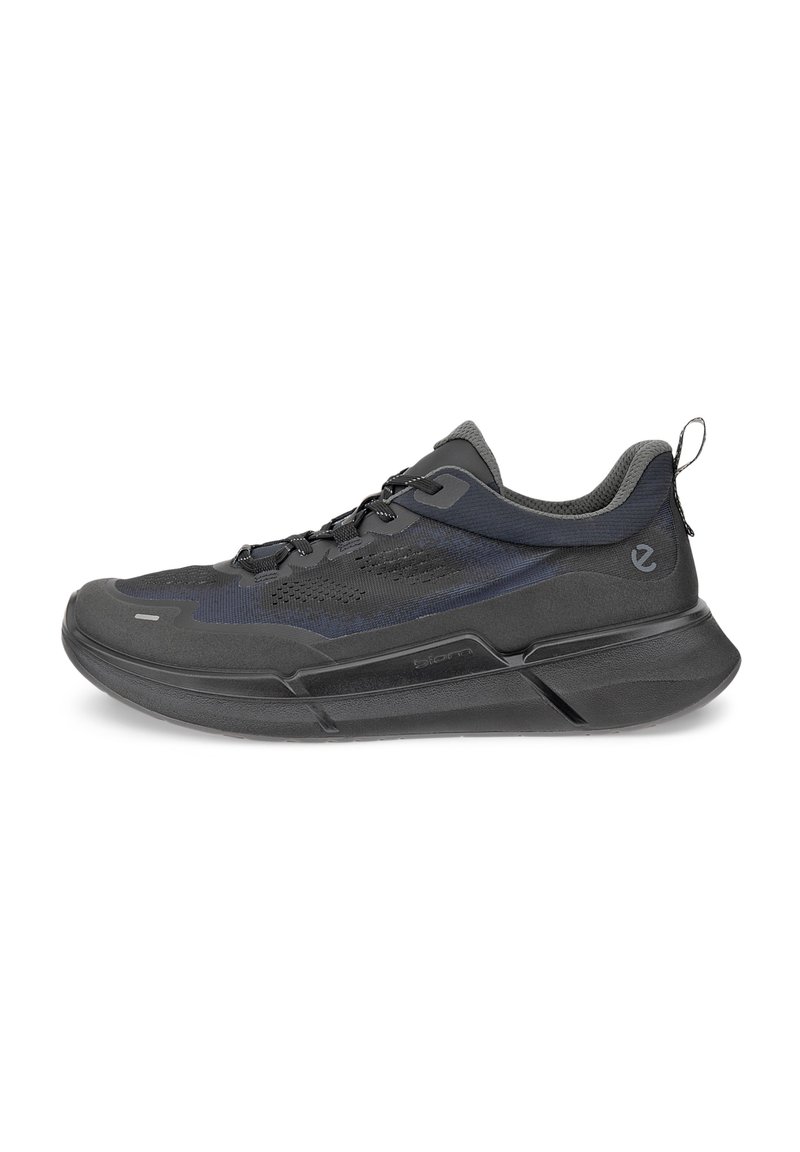 Black athletic shoe featuring a textured fabric upper, mesh panels, and a sturdy rubber sole. Design includes a pull tab at the rear.
