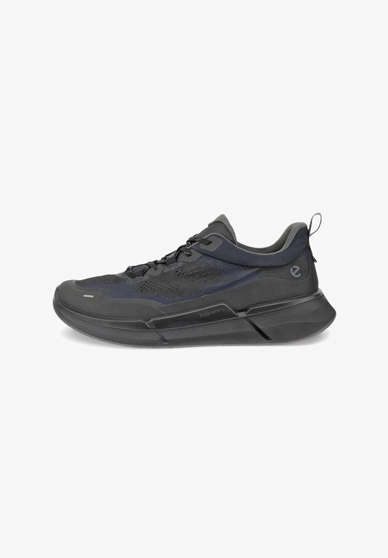 Black athletic shoe featuring a textured fabric upper, mesh panels, and a sturdy rubber sole. Design includes a pull tab at the rear.
