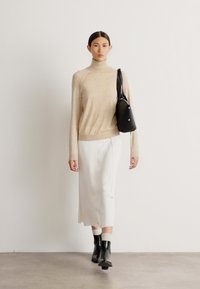 Beigžš turtlenecks, balts svārki un melnas potītes zābaki. Mazs melns rokassomiņa nēsāta uz pleca, ar gludu auduma tekstūru.