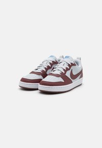 Baskets Nike avec une tige en cuir gris, des accents bordeaux, une semelle en caoutchouc blanche et un logo bleu sur la languette. Extrémité perforée texturée.