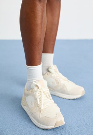 Heledad beezid spordijalatsid, millel on võrgu- ja nahkdetailid. Omab logo, nööpimise disaini ning pehmendatud talla. Kanda valgete sokkidega.