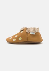 Scarpa in pelle marrone con una texture morbida, decorata con ricami di fiori bianchi e gialli, e un polsino beige arricciato all'apertura.