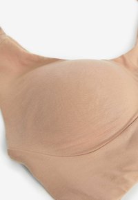 Goli push-up grudnjak s glatkom tkaninom, teksturiranom površinom i bešavnim rubovima, ima zaobljen oblik i podesive naramenice.