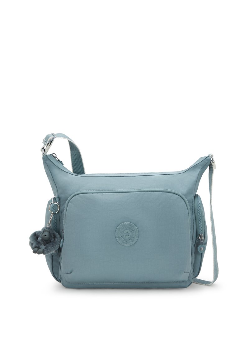 Borsa crossbody azzurro chiaro con tasca frontale con zip, zip laterali, tracolla regolabile e un piccolo portachiavi di peluche attaccato a un lato.