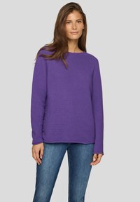 Lila strukturierter Pullover mit Rundhalsausschnitt und langen Ärmeln, kombiniert mit blauer Jeans. Verfügt über eine lockere Passform und ein geripptes Muster.