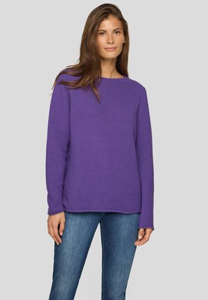Lila strukturierter Pullover mit Rundhalsausschnitt und langen Ärmeln, kombiniert mit blauer Jeans. Verfügt über eine lockere Passform und ein geripptes Muster.