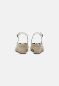 Sandalias de cuña blancas con un tacón texturizado y tejido. Correa ajustable, forro interior de lunares y un acabado de material suave.