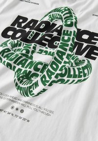 Camiseta blanca con texto en verde y negro en tipografía negrita. El diseño incluye texto entrelazado y una cita debajo para mayor detalle.