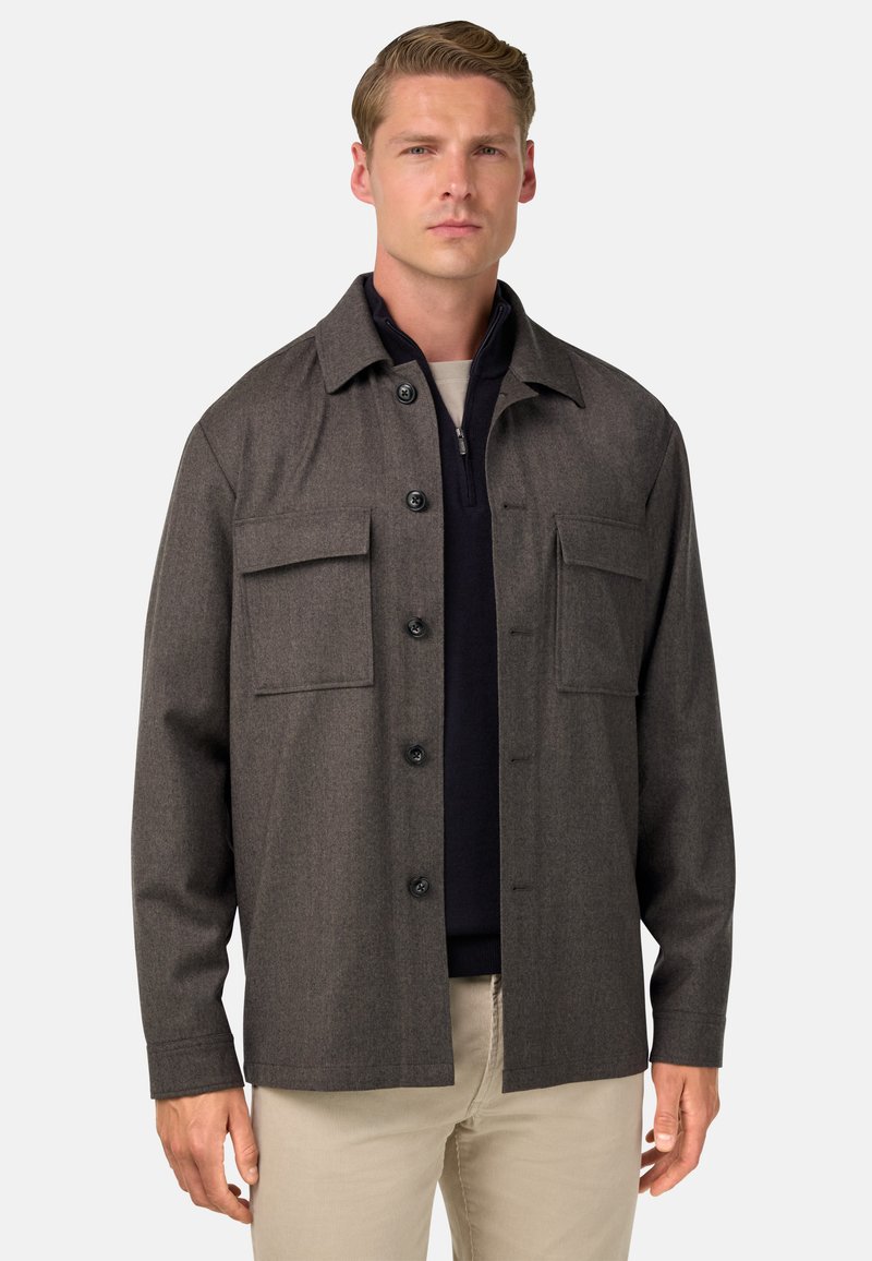 Chaqueta de franela gris con botones en el frente, dos bolsillos en el pecho y un dobladillo recto. Presenta un cuello con solapas y una tela texturizada.