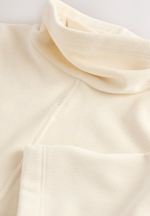 Krämfärgad ribbad polokrage top i mjukt material, med en vikbar krage och sömdetaljer, med en slät, texturerad yta.