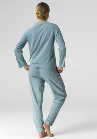 Jasnoniebieska bluzka z długim rękawem zestawiona z dopasowanymi spodniami w delikatny kwiatowy wzór. Miękki, elastyczny materiał o luźnym kroju.