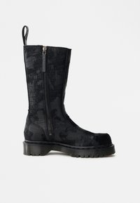 Melnas pusmēroga zābaks ar teksturētu rakstu, sānu rāvējslēdzēju, aizmugurēlu cilpu, biezu rievotu zoli un apaļu purngalu.