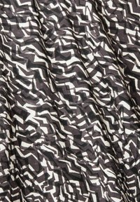 Tessuto a motivi in bianco e nero con forme astratte a zigzag e geometriche, con una texture liscia e un peso medio.