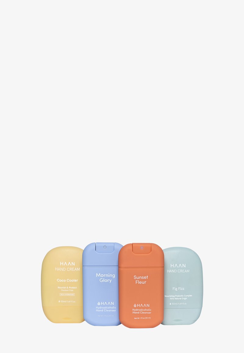 Vier Handcremebehälter in Pastellfarben: Gelb, Blau, Orange und Grün. Jeder hat eine abgerundete Form mit Etiketten und Klappdeckeln.