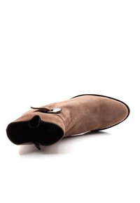 Suedesandal i ljusbrunt med spetstå och en slank silhuett. Har en dragkedjestängning och en dekorativ metallackent.