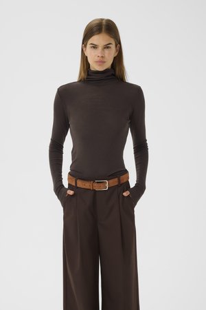 Brown turtleneck top with long sleeves, paired with high-waisted, wide-leg brown trousers and a textured brown belt with a silver buckle.