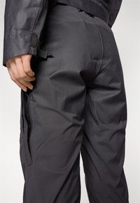 Black, textured fabric pants with a fitted design, featuring a side zipper pocket and adjustable waist detail.