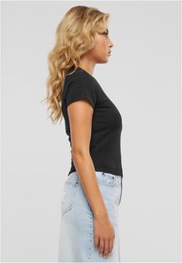 Must peale sobiv t-särk lühikeste varrukatega, kombineeritud helesinise teksaseeliku, millel on kleidi küljes tasku ja hele pesu tekstuur.