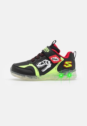 Sapatilhas pretas com verde néon, com um upper texturizado, gráfico de dinossauro, detalhes em vermelho e solas que iluminam. Apresenta um design com atacadores e faixa.