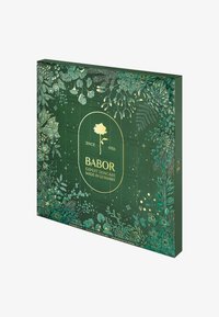 Green cardboard box featuring intricate floral and foliage patterns, gold accents, and a central logo. Contains 24 compartments for skincare products.