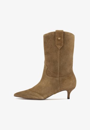 Brown suede ankle boot with pointed toe and low kitten heel. Features decorative stitching and a tab at the back for easy wear.